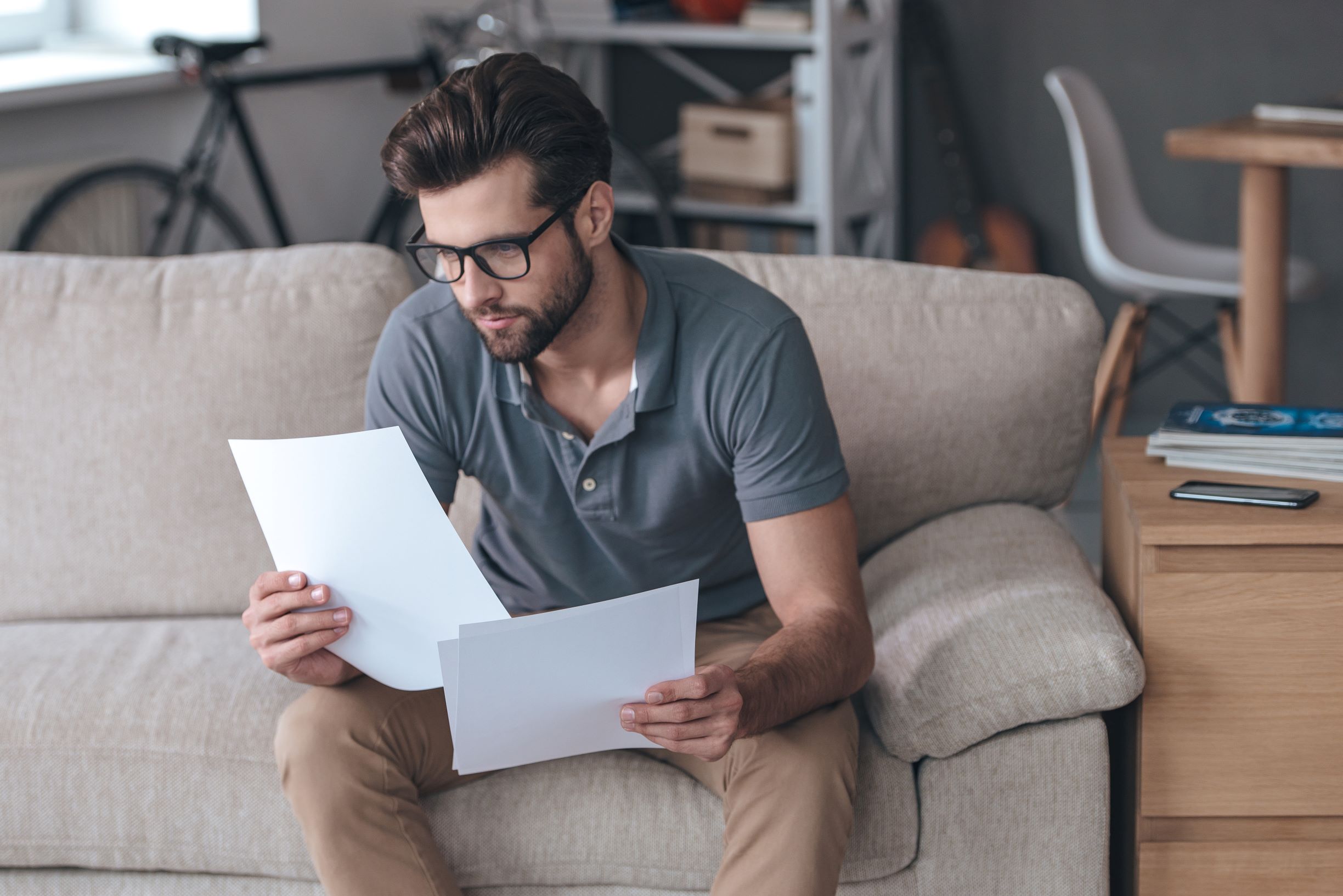 Man looking dismayed as he’s examining bills