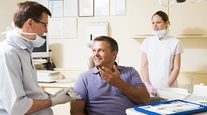 Dentist discusses dental procedures with a patient.