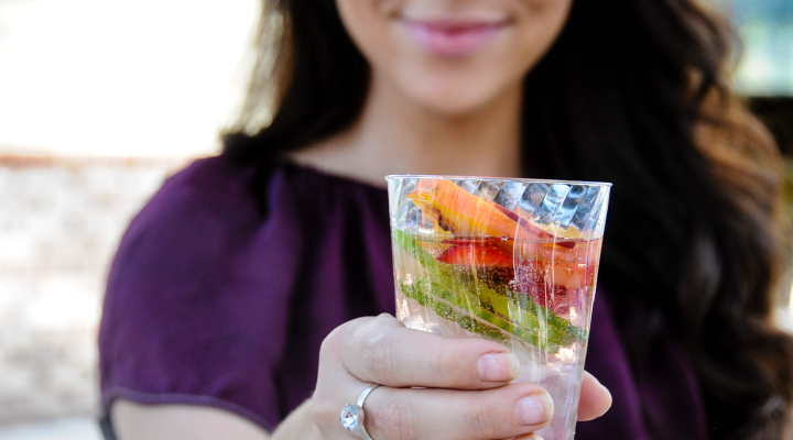 Woman offering a glass of cucumber- and strawberry-infused water