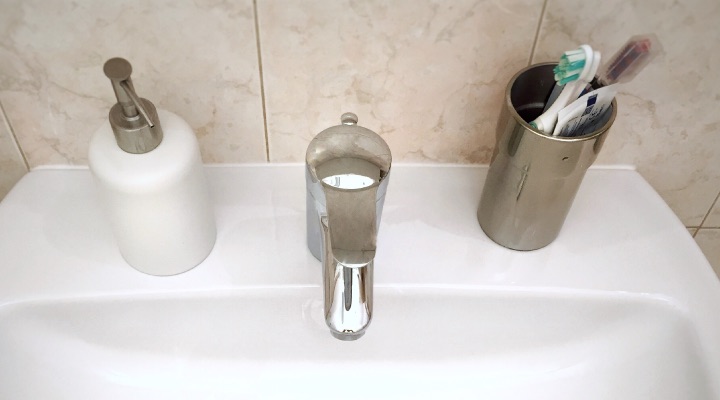 Bathroom sink with toothbrush holder, toothbrush and toothpaste